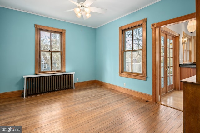 spare room with ornamental molding, plenty of natural light, light wood-type flooring, and radiator heating unit