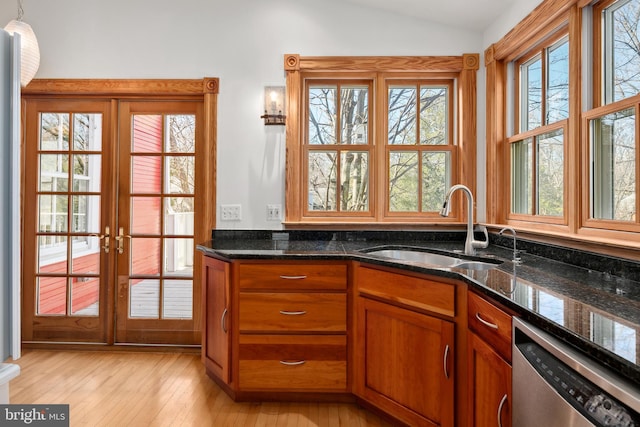 kitchen with lofted ceiling, sink, pendant lighting, dishwasher, and dark stone counters