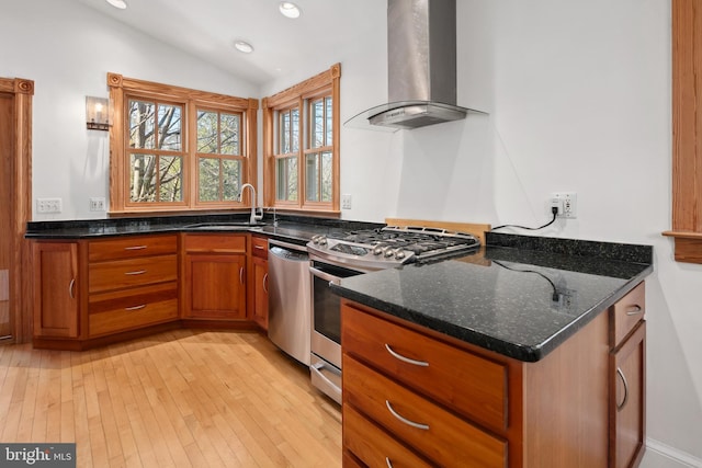 kitchen featuring lofted ceiling, exhaust hood, sink, dark stone counters, and appliances with stainless steel finishes