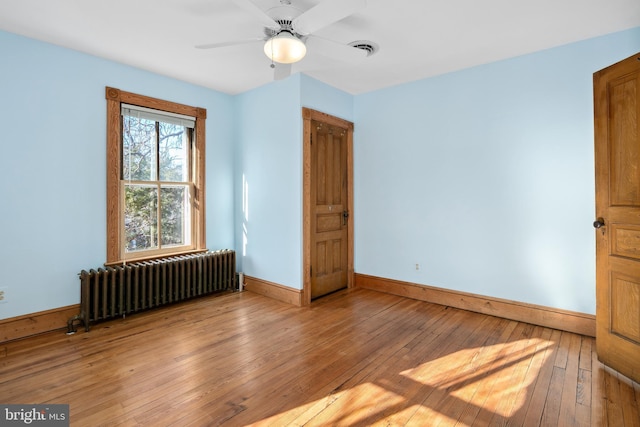 unfurnished bedroom featuring ceiling fan, light hardwood / wood-style floors, and radiator heating unit