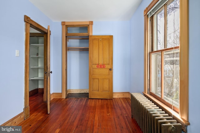 interior space featuring dark wood-type flooring, a closet, and radiator heating unit