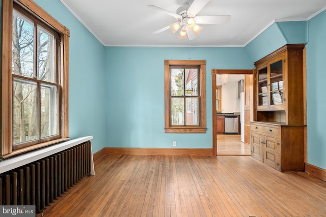 unfurnished room with radiator, ornamental molding, light hardwood / wood-style floors, and plenty of natural light