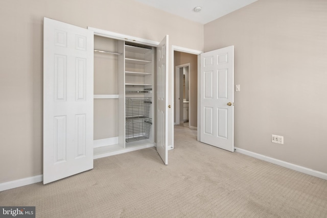 unfurnished bedroom featuring light colored carpet and a closet