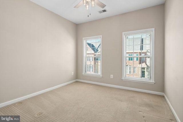 carpeted spare room featuring ceiling fan and a wealth of natural light