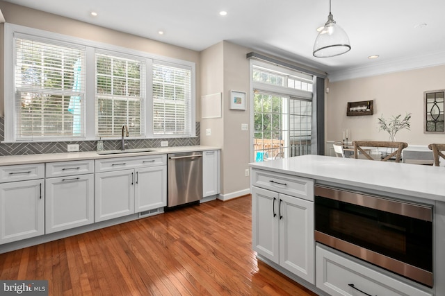 kitchen with hanging light fixtures, backsplash, sink, and appliances with stainless steel finishes