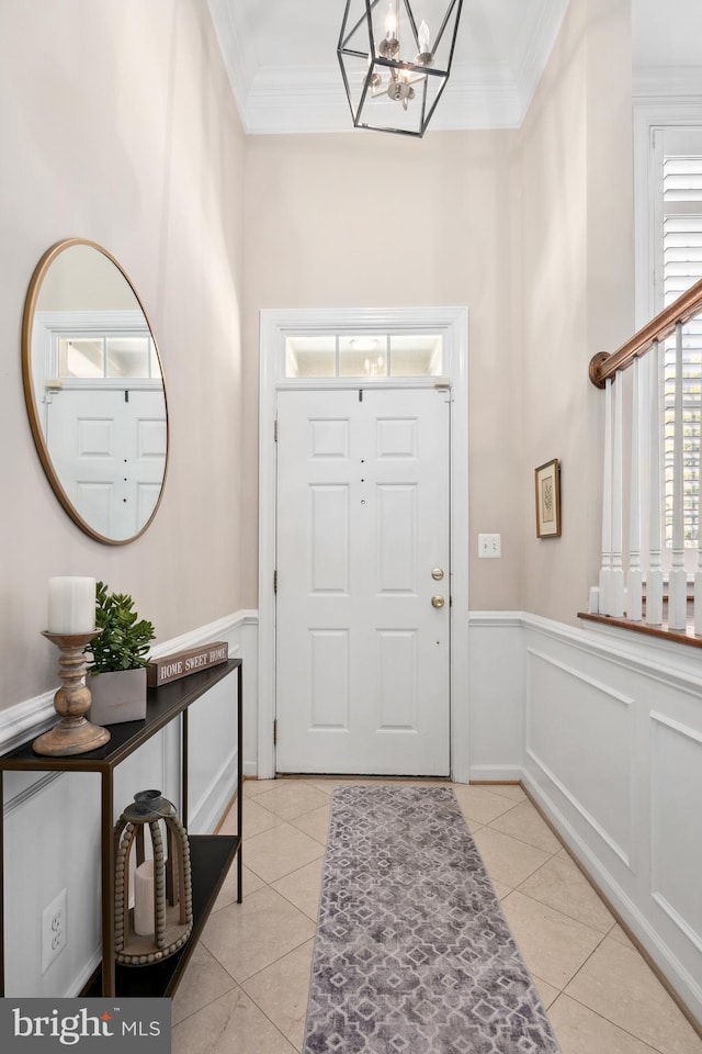 foyer featuring an inviting chandelier, ornamental molding, and light tile patterned floors