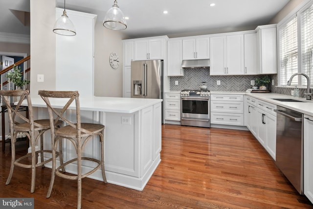 kitchen featuring sink, white cabinetry, hanging light fixtures, a kitchen breakfast bar, and premium appliances