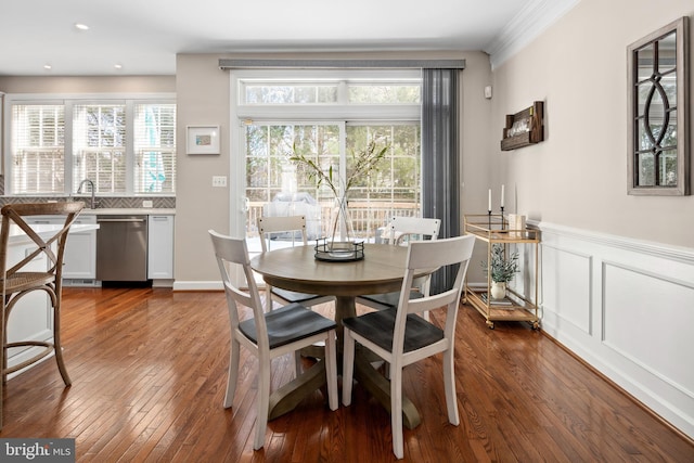 dining room with dark wood-type flooring, ornamental molding, and plenty of natural light