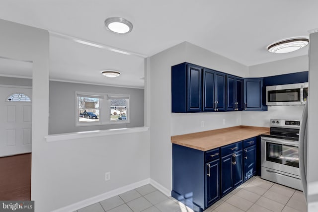 kitchen with wood counters, stainless steel appliances, blue cabinetry, light tile patterned floors, and crown molding