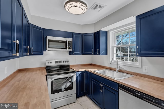 kitchen featuring sink, appliances with stainless steel finishes, blue cabinetry, and butcher block counters