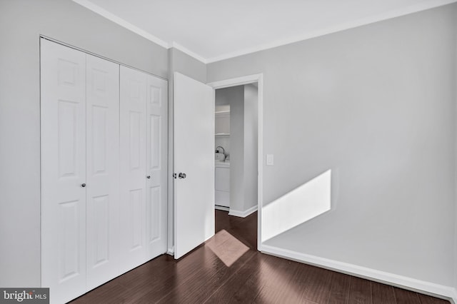 unfurnished bedroom featuring washer / dryer, a closet, and dark hardwood / wood-style flooring