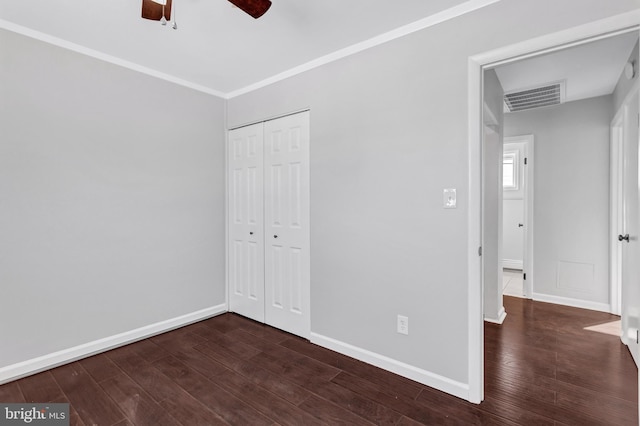 unfurnished bedroom featuring dark wood-type flooring, a closet, ornamental molding, and ceiling fan