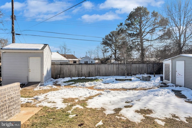 yard layered in snow featuring a storage unit