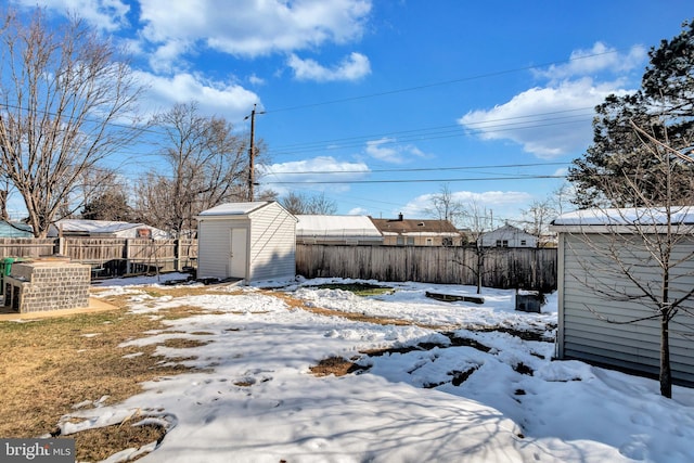 snowy yard featuring a storage shed