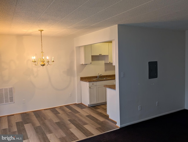 kitchen featuring an inviting chandelier, white cabinetry, wood-type flooring, electric panel, and sink