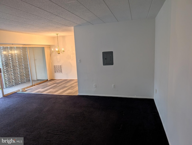 carpeted empty room featuring electric panel and an inviting chandelier