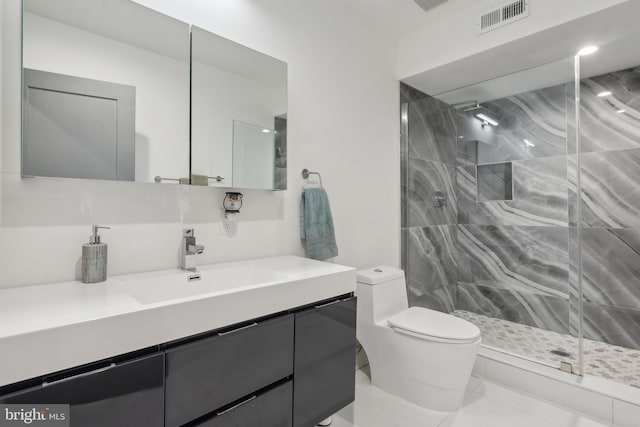 bathroom with vanity, tiled shower, and toilet