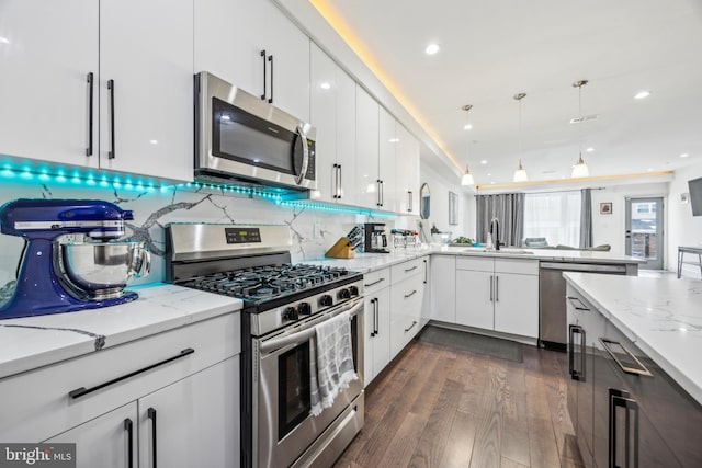 kitchen featuring sink, appliances with stainless steel finishes, white cabinetry, light stone counters, and tasteful backsplash