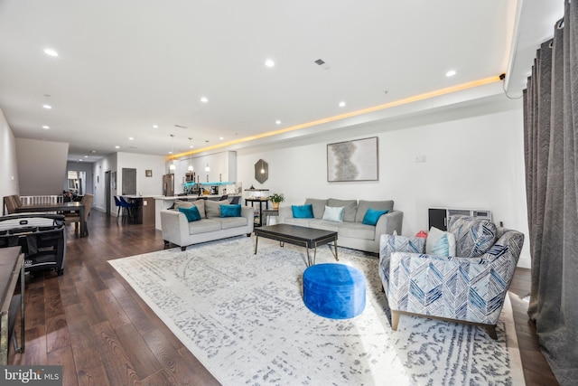 living room with dark wood-type flooring and a tray ceiling