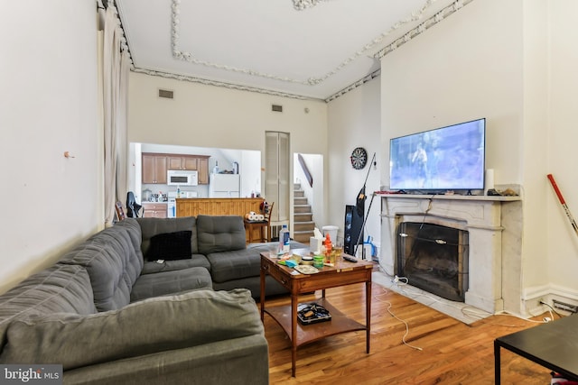 living room with a towering ceiling and light wood-type flooring