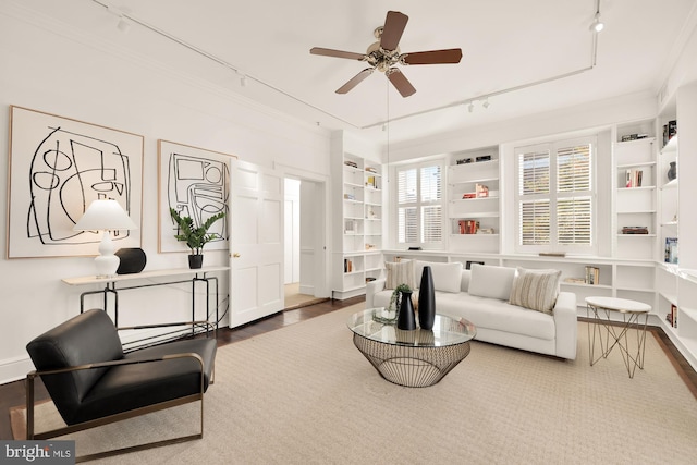 interior space with built in features, wood-type flooring, ceiling fan, crown molding, and track lighting