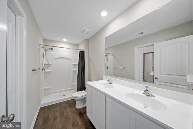 bathroom with walk in shower, vanity, wood-type flooring, and toilet