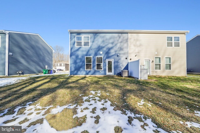 snow covered rear of property with a lawn and cooling unit