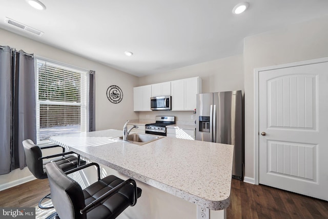 kitchen with sink, dark wood-type flooring, an island with sink, stainless steel appliances, and white cabinets