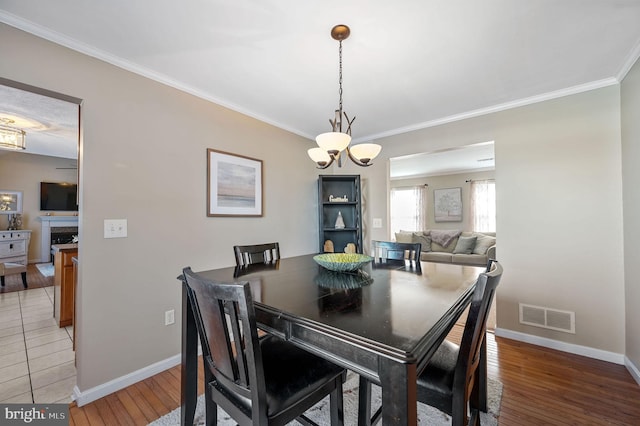 dining area featuring hardwood / wood-style flooring, ornamental molding, and a notable chandelier