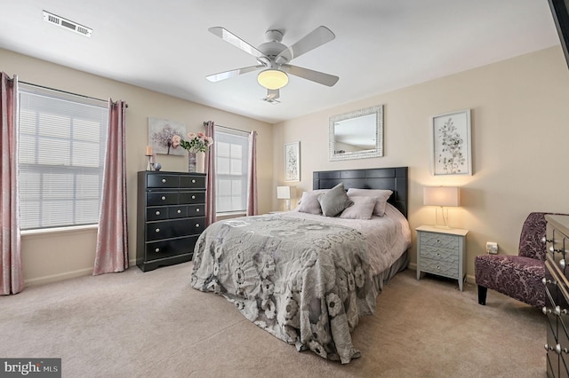 bedroom with ceiling fan, light colored carpet, and multiple windows