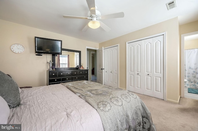 bedroom featuring two closets, light colored carpet, and ceiling fan