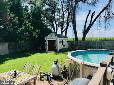 view of swimming pool with a lawn and a storage unit