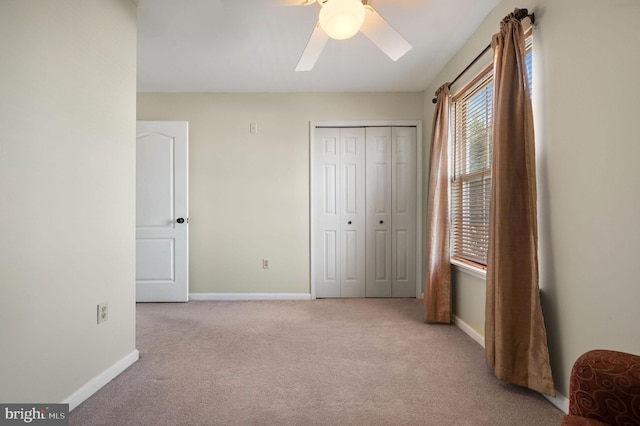 unfurnished bedroom with light colored carpet, a closet, and ceiling fan