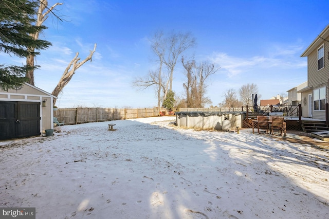 yard covered in snow with a pool side deck and a storage unit