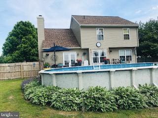 back of house featuring a fenced in pool and a lawn