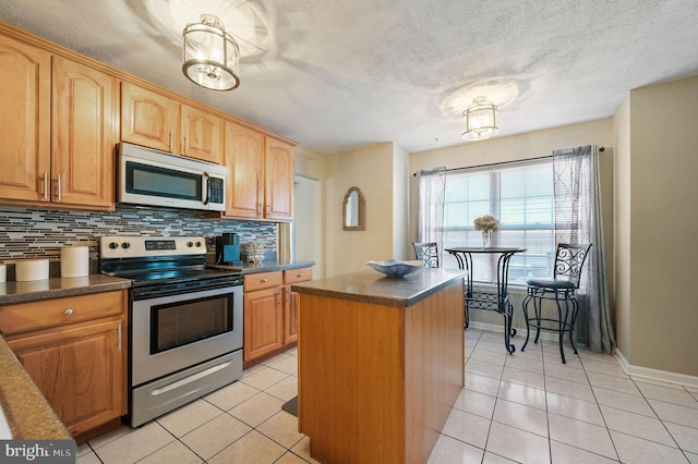 kitchen featuring light tile patterned floors, decorative backsplash, stainless steel appliances, and a kitchen island