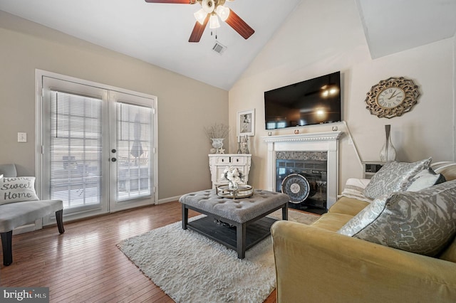 living room featuring ceiling fan, hardwood / wood-style floors, high vaulted ceiling, a fireplace, and french doors