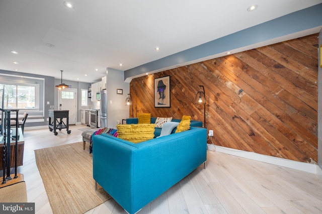 living area with light wood-style flooring, wooden walls, and recessed lighting