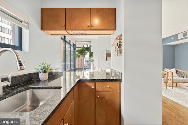 kitchen with light hardwood / wood-style floors, sink, and dark stone countertops