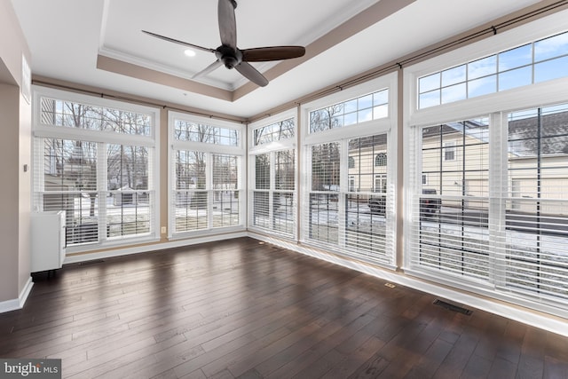 unfurnished sunroom featuring ceiling fan, a wealth of natural light, and a raised ceiling