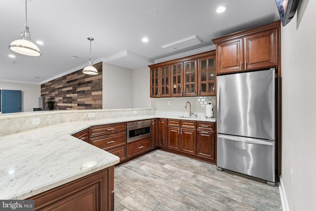 kitchen with appliances with stainless steel finishes, sink, decorative light fixtures, light stone countertops, and ornamental molding