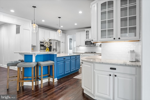 kitchen with white cabinetry, appliances with stainless steel finishes, a center island, and blue cabinets