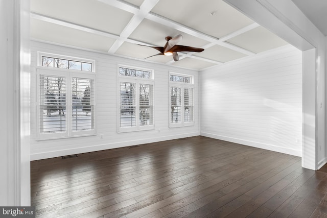 empty room featuring coffered ceiling, dark hardwood / wood-style floors, and beam ceiling