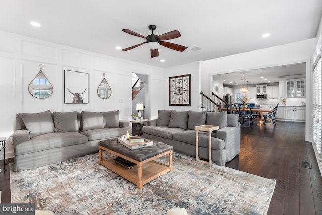 living room featuring dark wood-type flooring and ceiling fan