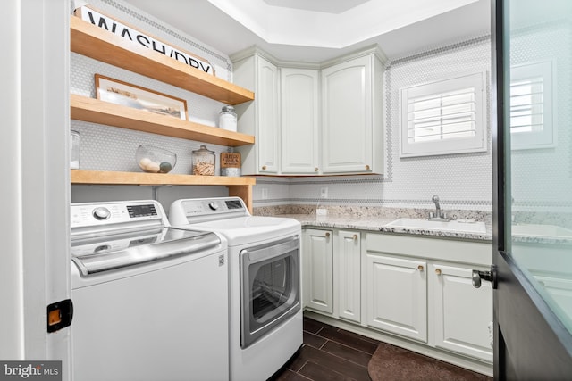 washroom with sink, washing machine and dryer, and cabinets