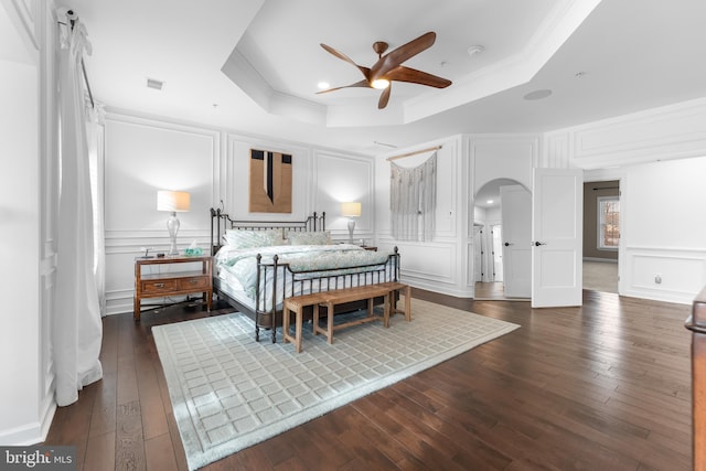 bedroom with ceiling fan, a raised ceiling, crown molding, and dark hardwood / wood-style floors