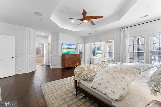 bedroom featuring ceiling fan, crown molding, dark hardwood / wood-style flooring, and a raised ceiling