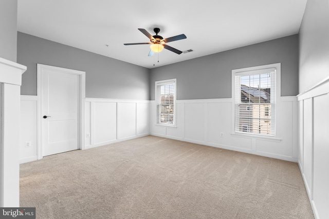 unfurnished bedroom with ceiling fan, multiple windows, and light carpet