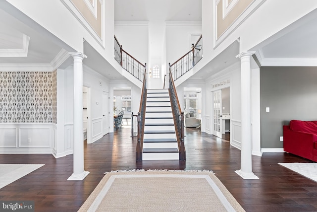 foyer featuring a high ceiling, dark hardwood / wood-style floors, and ornate columns