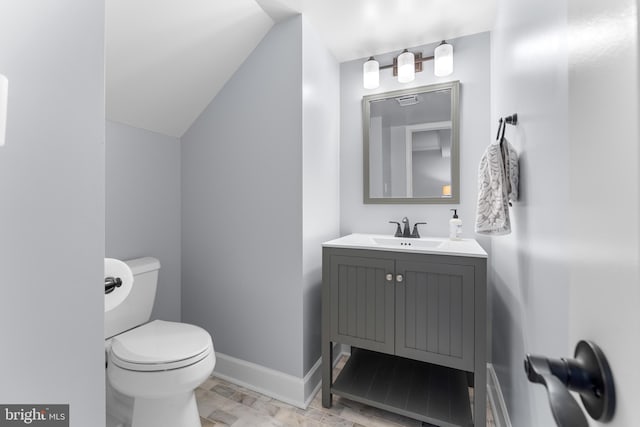 bathroom featuring toilet, vaulted ceiling, and vanity